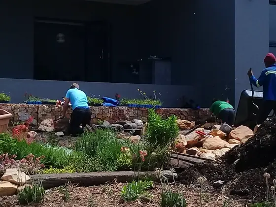 Crew planting a stone-edged bed in front of a modern house